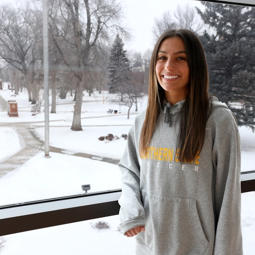 Female student leaning against window with snowy background