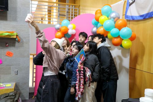 International students take a photo in front of a balloon arch