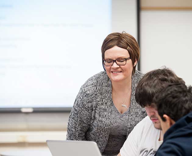 A professor smiles at the front of the class