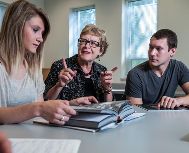 Students and a professor work together at a table