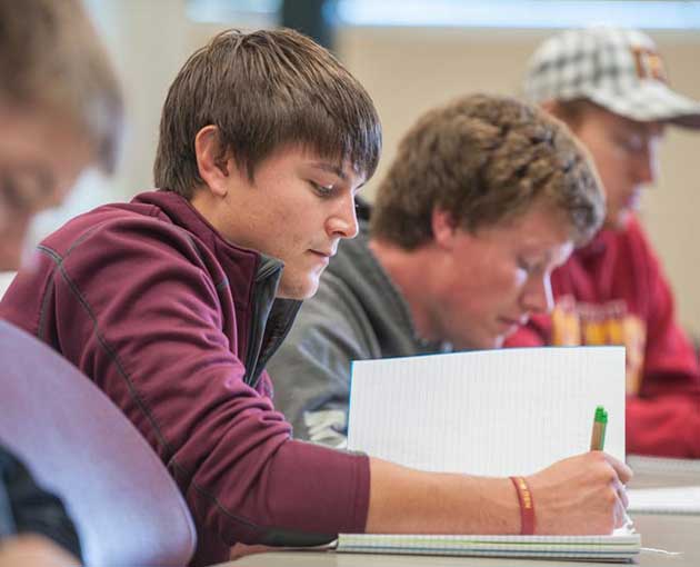 Two students write papers in class