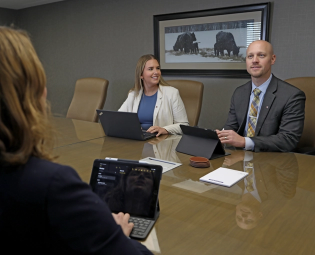 Three people sitting around a conference table