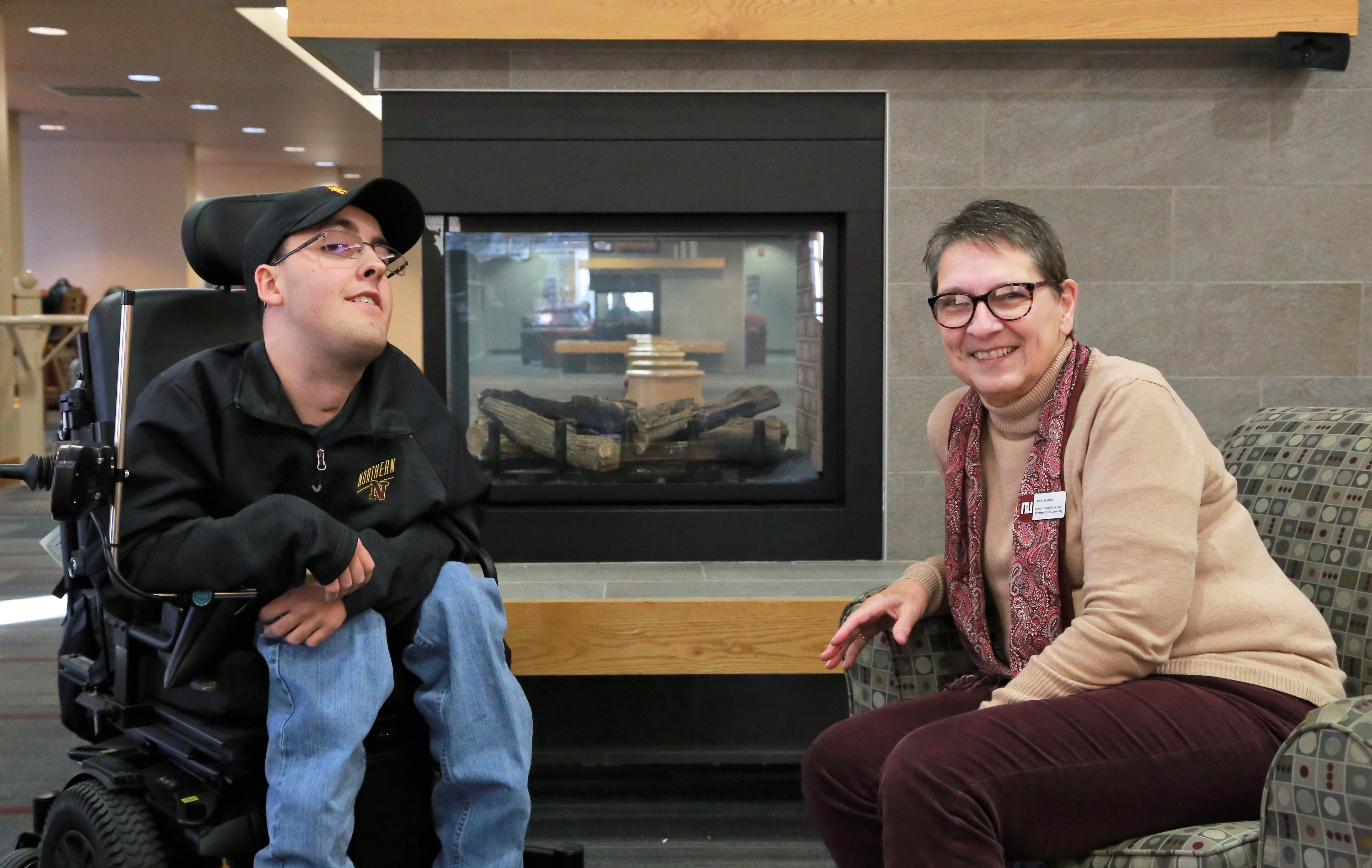 Student and employee near fireplace in student center