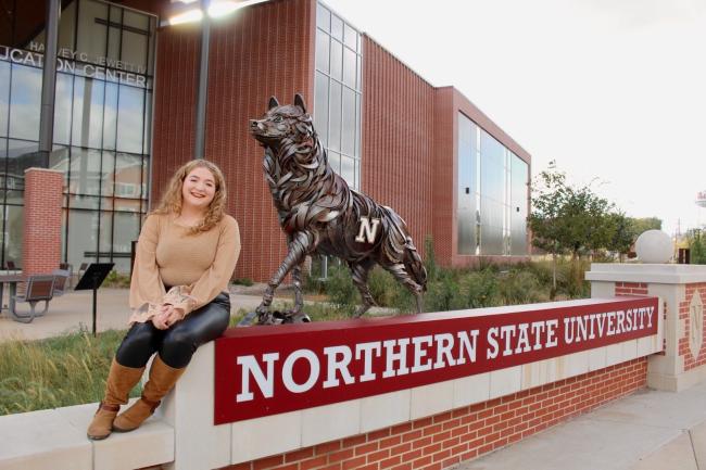 Young woman sitting by wolf statue outside science center