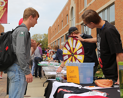 Students spinning a wheel at an outdoor table on campus