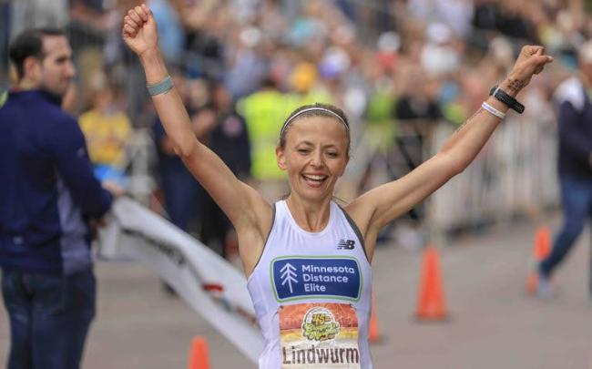 Female runner crossing finish line, arms raised
