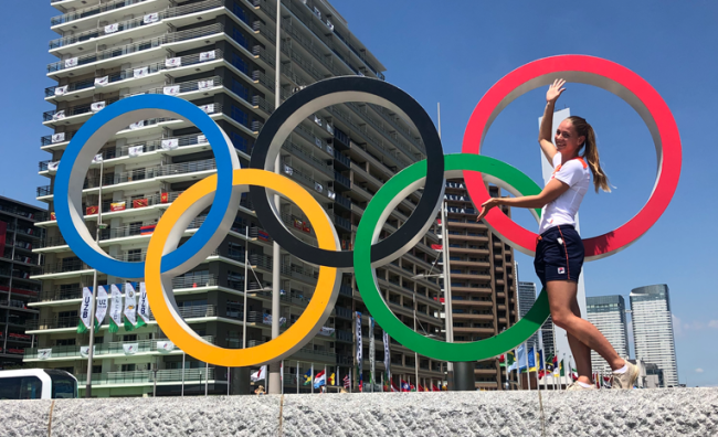 Woman standing by sculpture of Olympic rings