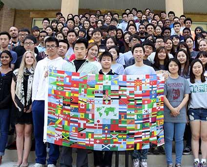 A crowd of business students displays an international flag