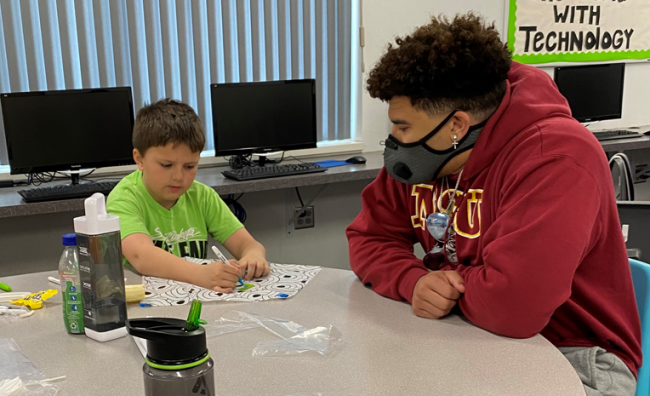 College student helping child at craft project