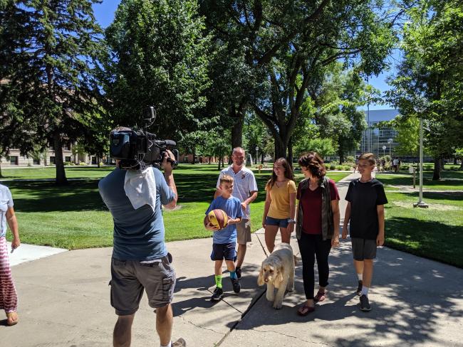Family walking on campus being filmed by TV camera crew